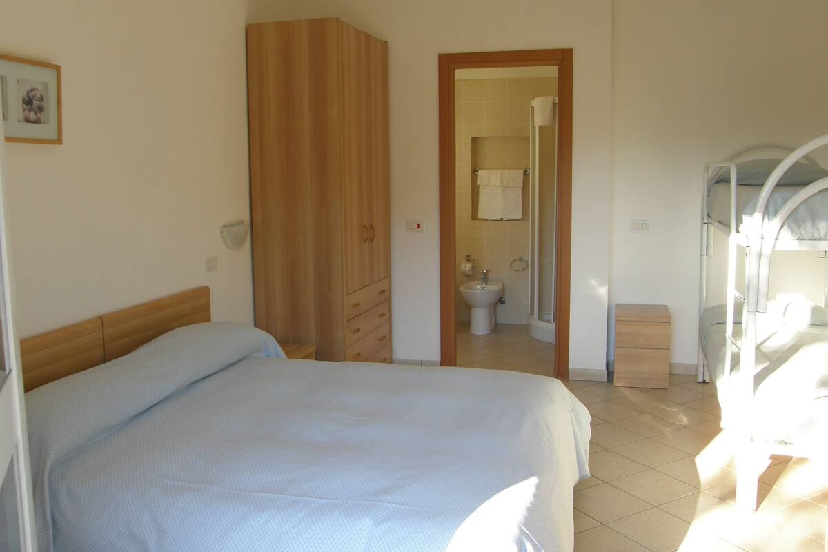 A bedroom with a bed, a wardrobe, a bathroom with a toilet, and a shower.