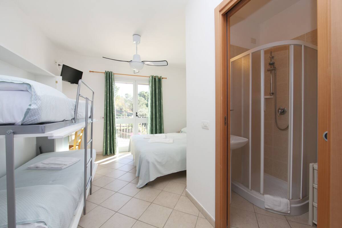 A room with bunk beds, a shower, and a bed with a view.