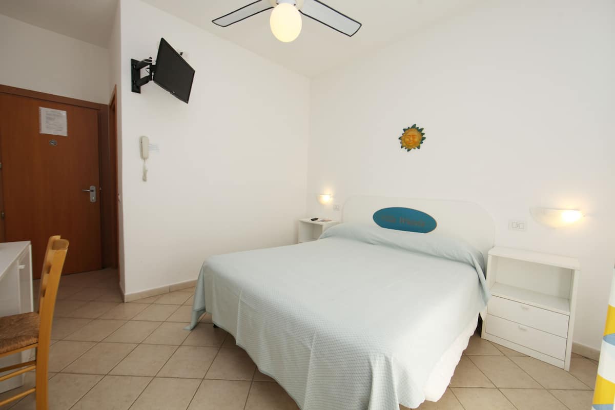 A bedroom with a bed, bedside tables, a desk, and a chair.