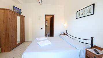 A bedroom with a bed, a wooden wardrobe, a nightstand, and a wall-mounted picture.