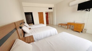 Habitació d'hotel amb dos llits, un taulell de nit de fusta, un escriptori i una televisió.