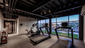 Une salle de sport équipée de tapis de course, de vélos d’appartement et d’un tapis de course placé au premier plan.