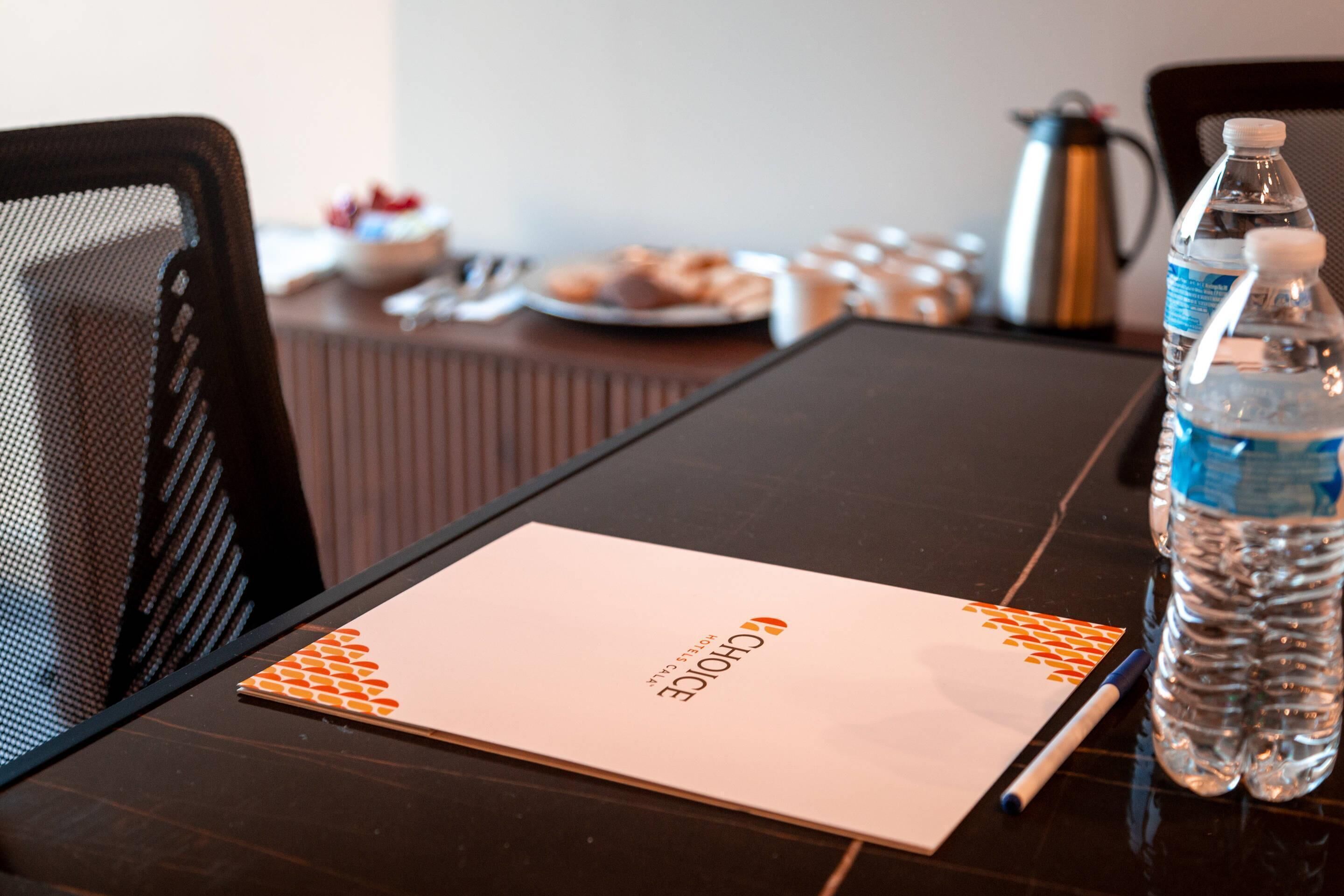 A conference table with a notepad, pen, and water bottles.