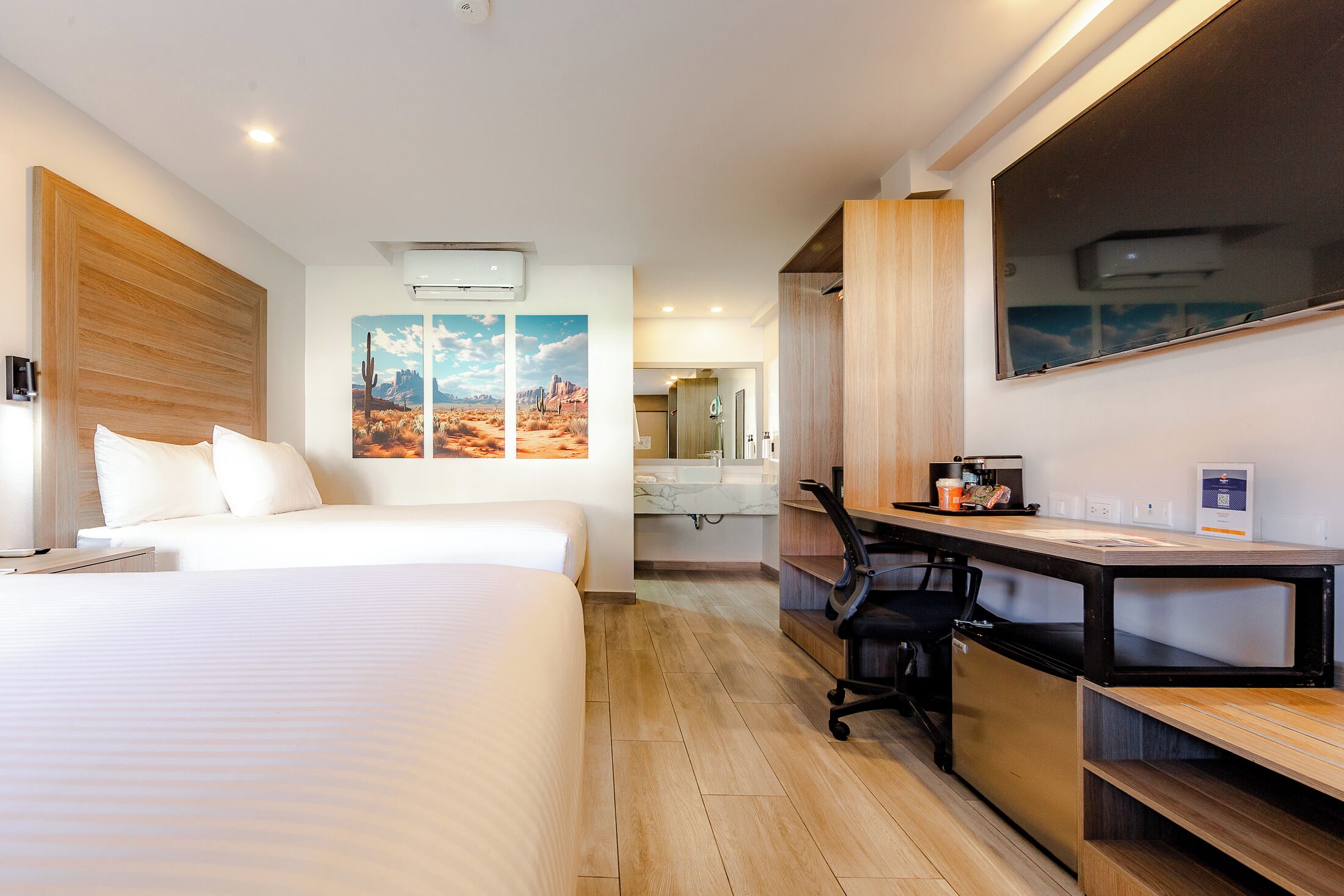 Habitación de hotel con cama, escritorio, silla y una obra de arte en la pared.