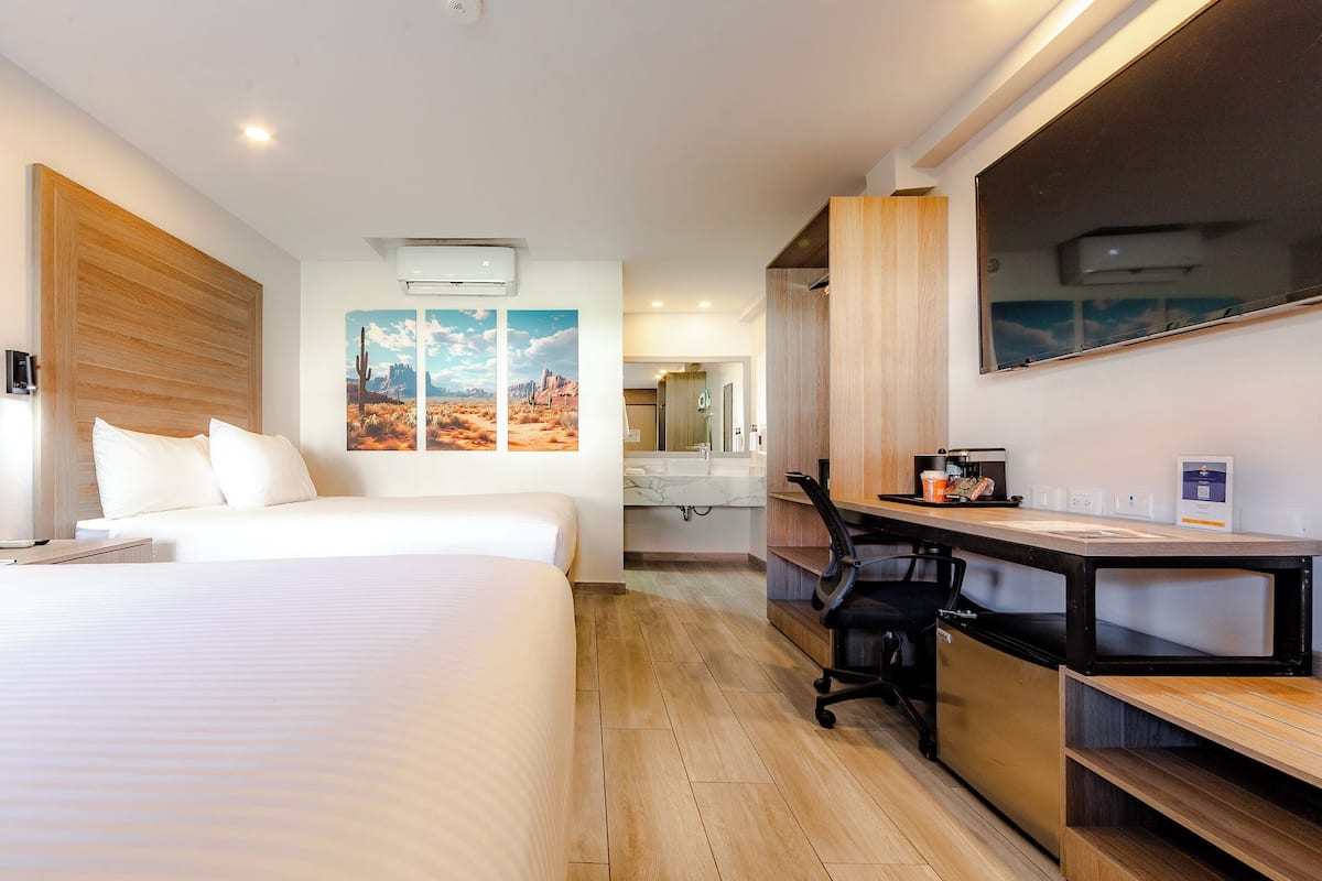 Habitación de hotel con cama, escritorio, silla y una obra de arte en la pared.