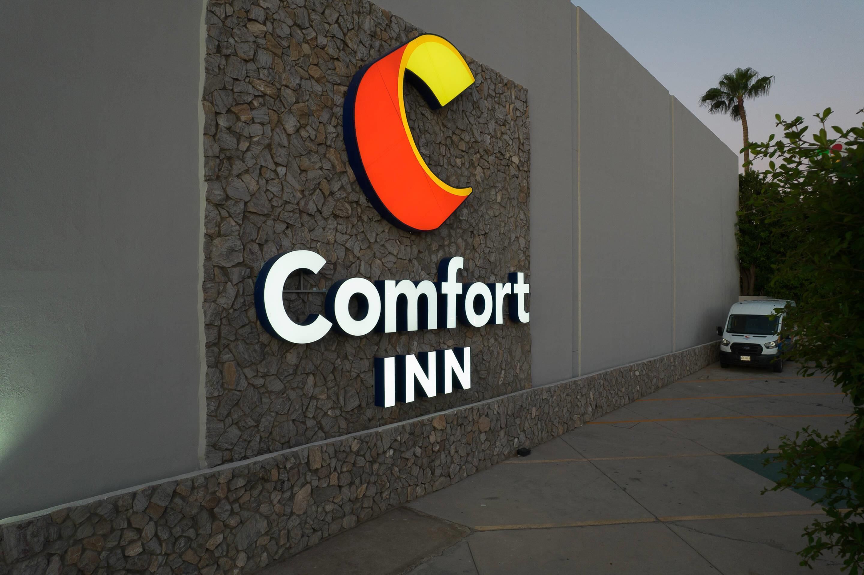 A Comfort Inn sign on a building with a stone facade and a parking lot.