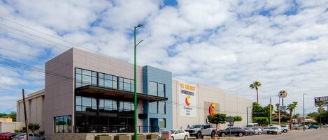 A modern building with a large glass entrance, a Comfort Inn sign, and a parking lot with several cars.