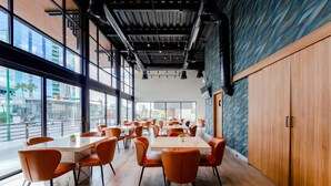 Un espace de restauration moderne avec de grandes fenêtres, un plancher en bois et des chaises orange.