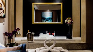 A bathroom with a bathtub, a mirror, and towels arranged in a heart shape. - Hotel Ticuán (Tijuana)