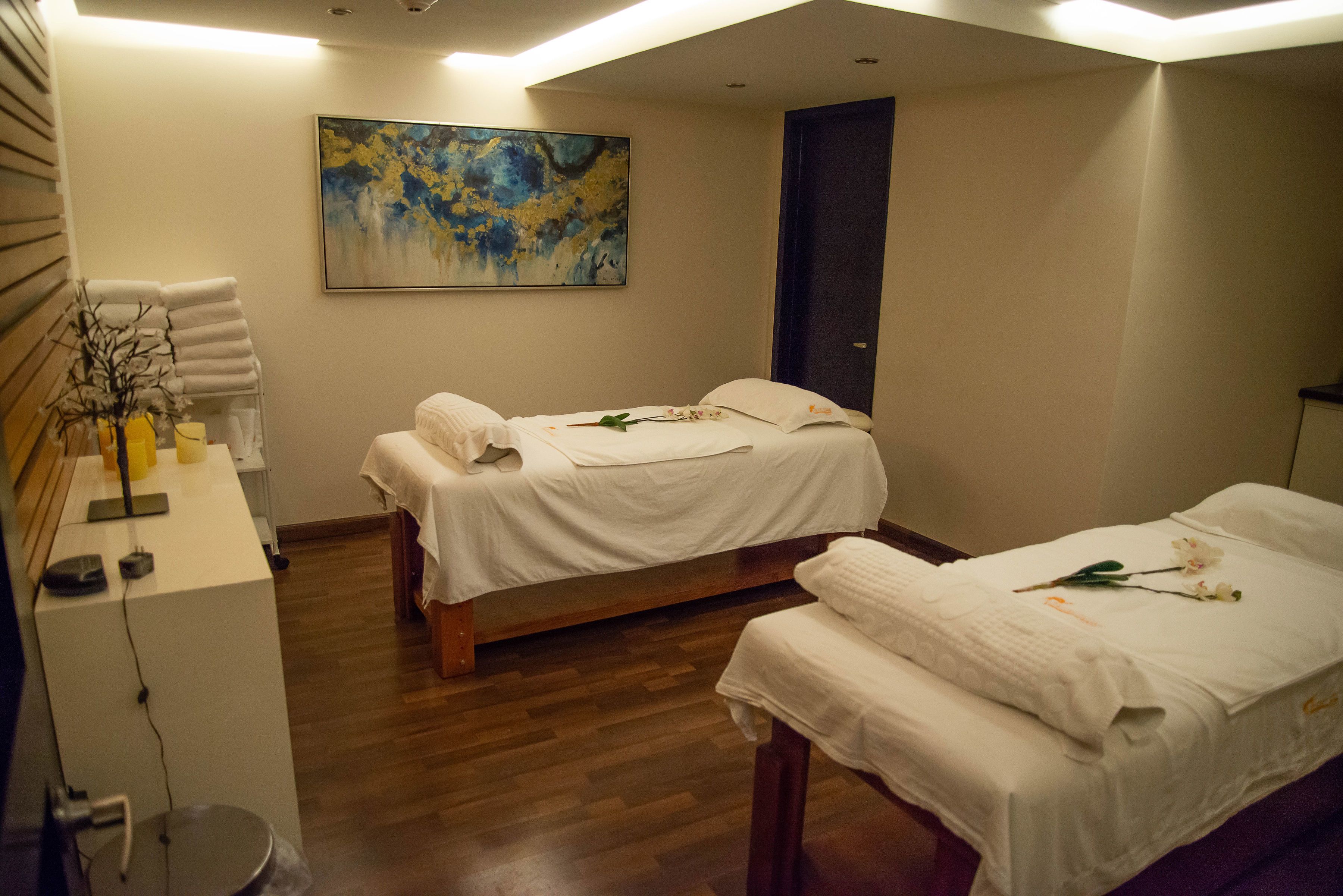 A hotel room with two beds, a painting on the wall, and a wooden floor.