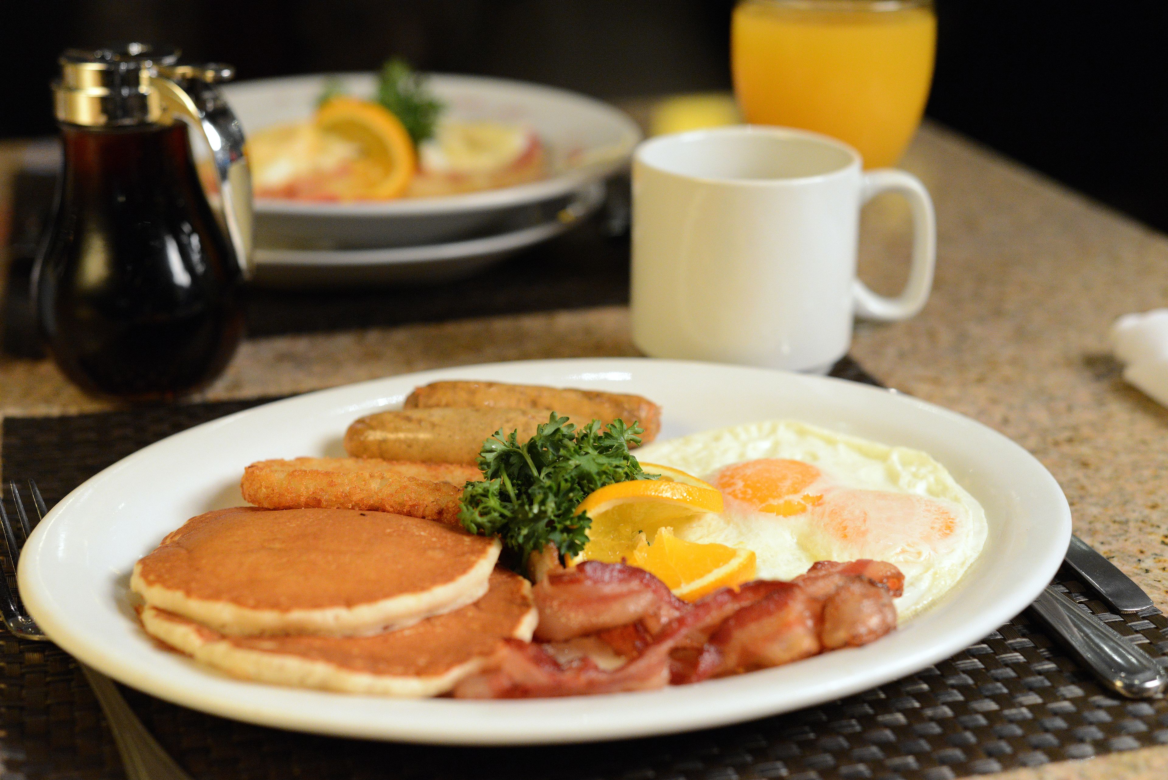 A breakfast plate with pancakes, bacon, eggs, and toast.