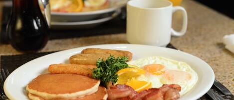 A breakfast plate with pancakes, bacon, eggs, and toast.
