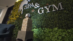 A wall with 'SPA & GYM' signage, a textured sculpture, and a dark-colored chair. - Hotel Ticuán (Tijuana)