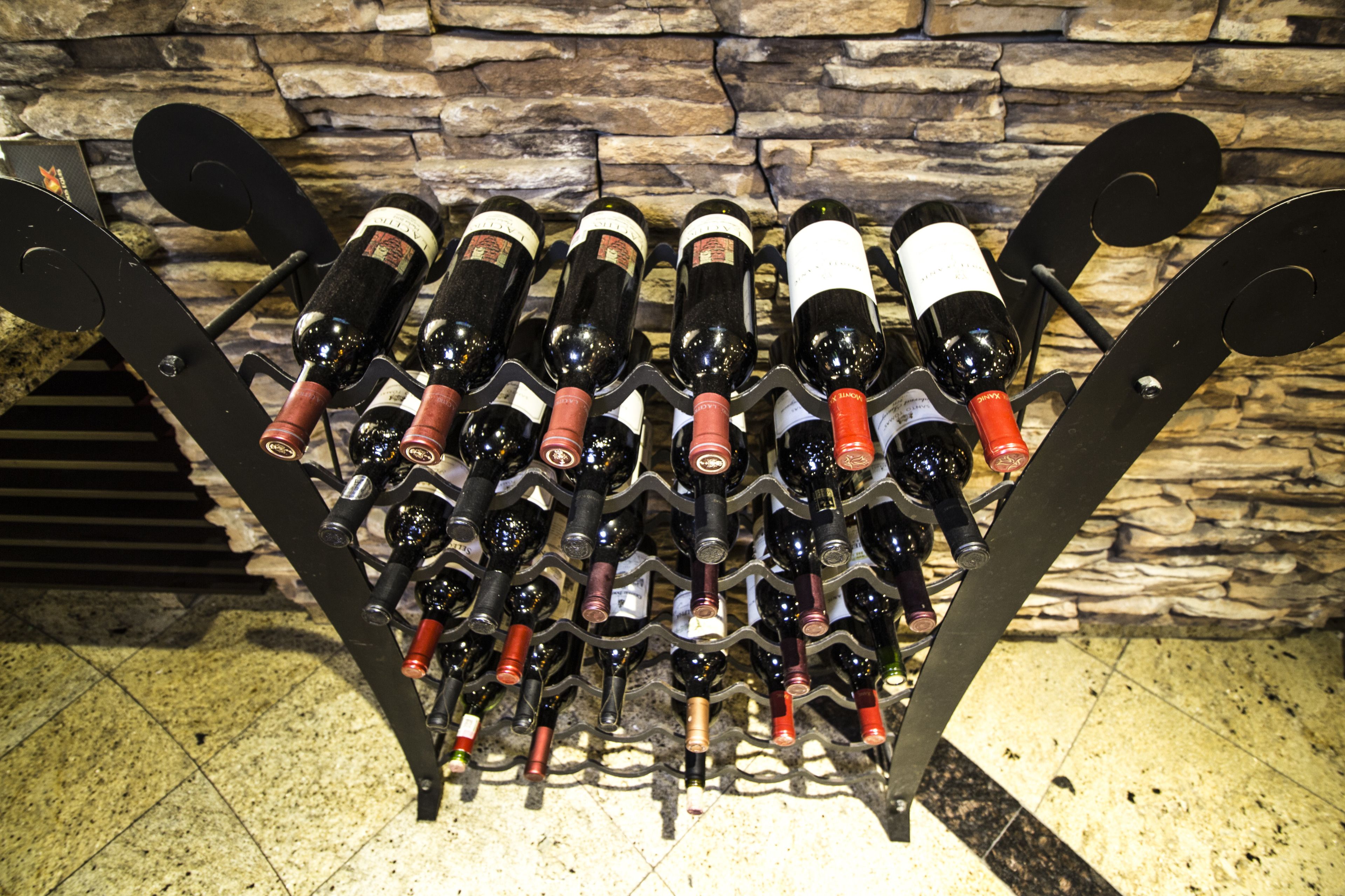 A wine rack with multiple bottles against a stone wall background.