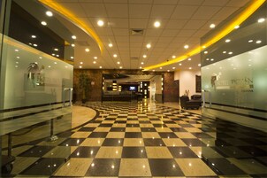 Un hall de hotel con suelo de cuadros, paredes de vidrio y un mostrador de recepción.