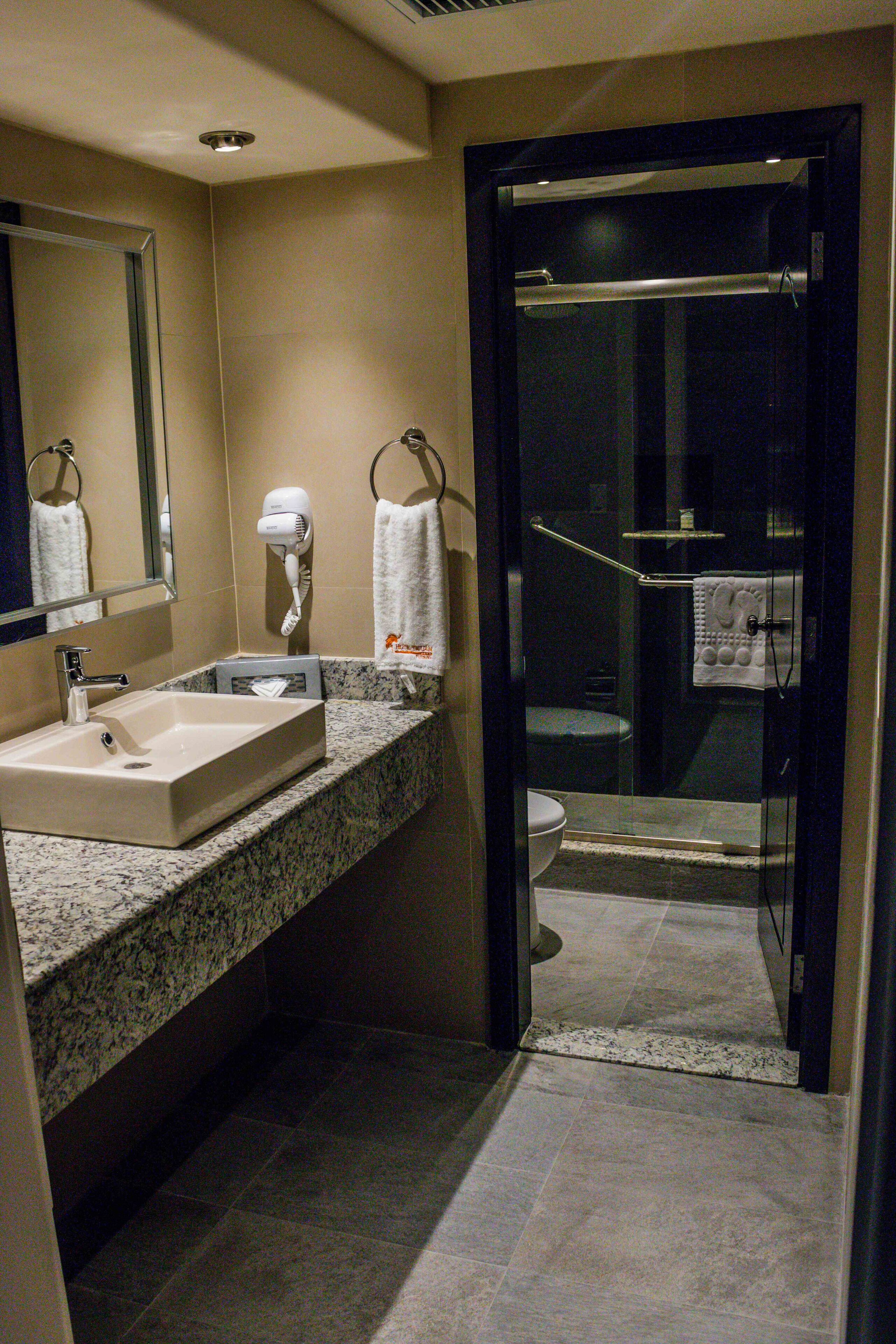 A bathroom with a sink, mirror, towel rack, and glass shower enclosure.