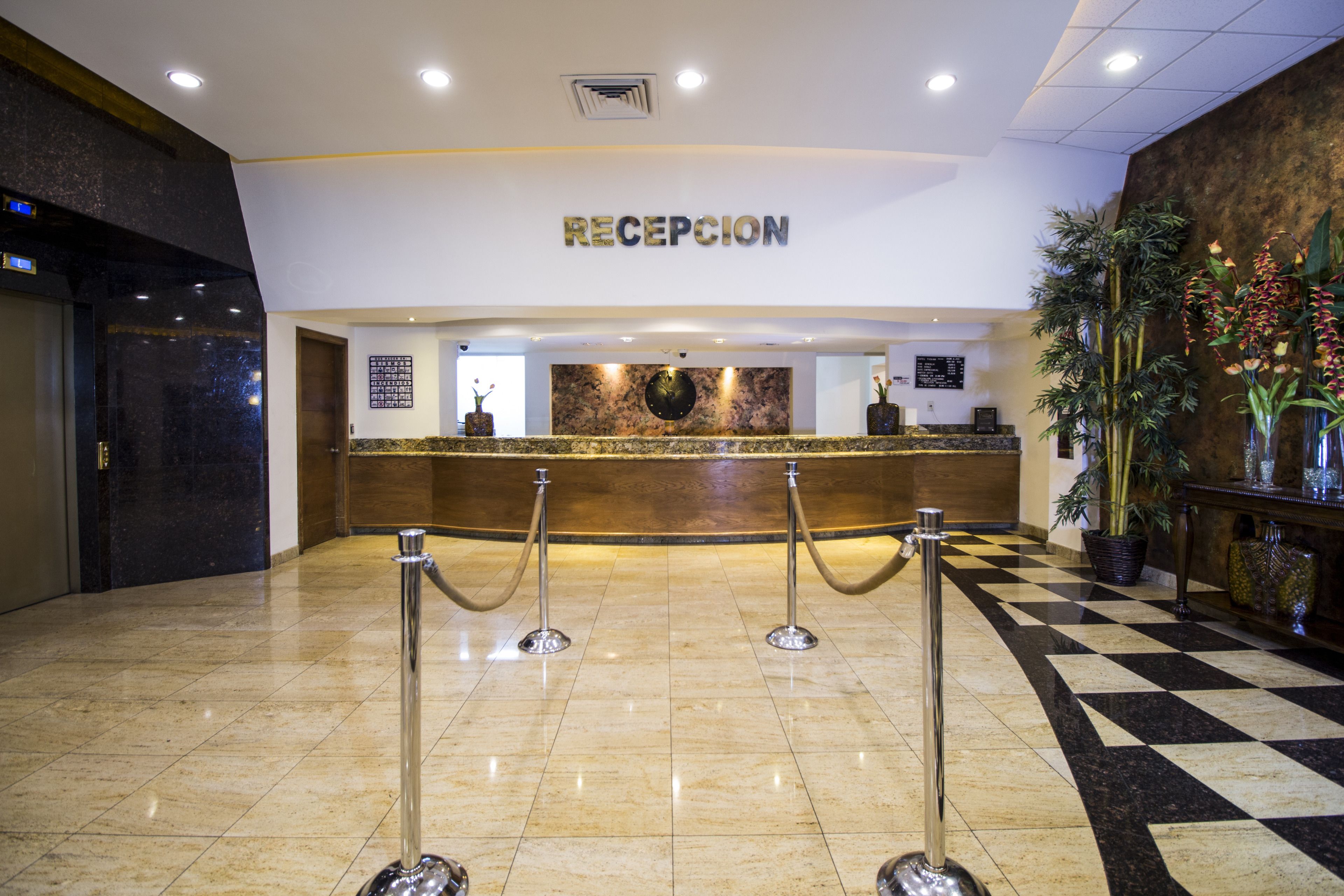 A reception area with a checkered floor, a reception desk, and a sign that reads "RECEPCION".