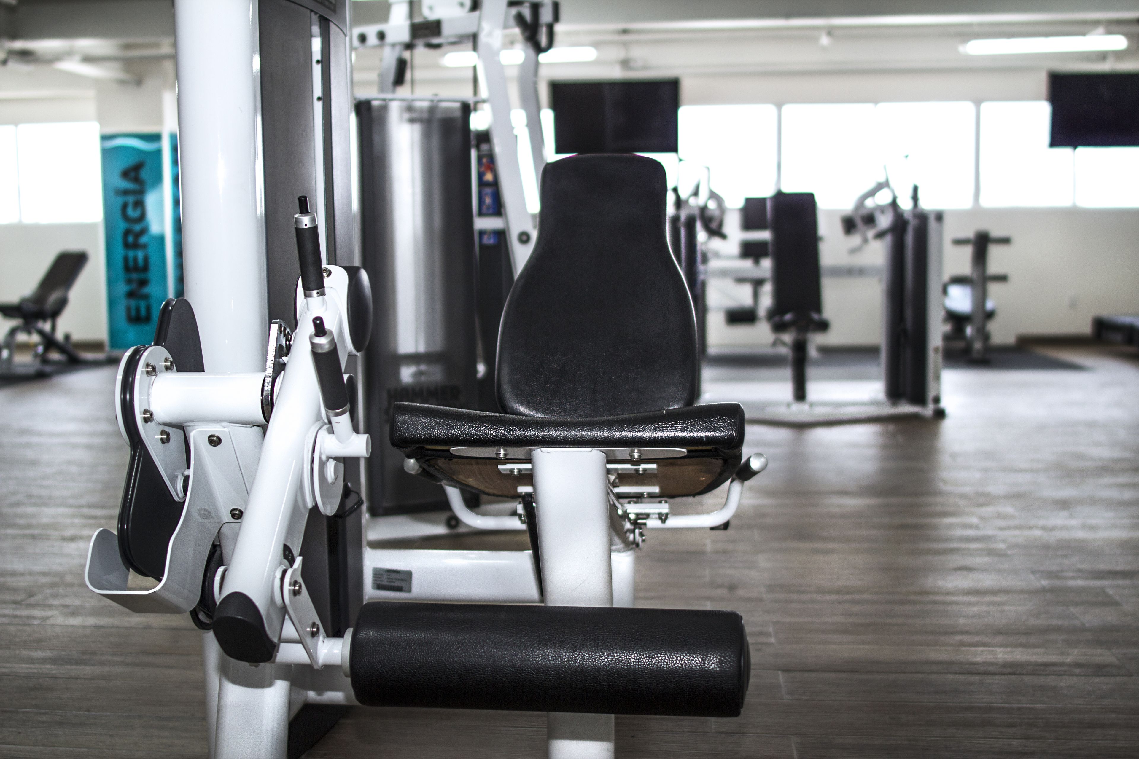 Un gimnasio con equipo de ejercicio, incluyendo una máquina de prensa de piernas y una banca.