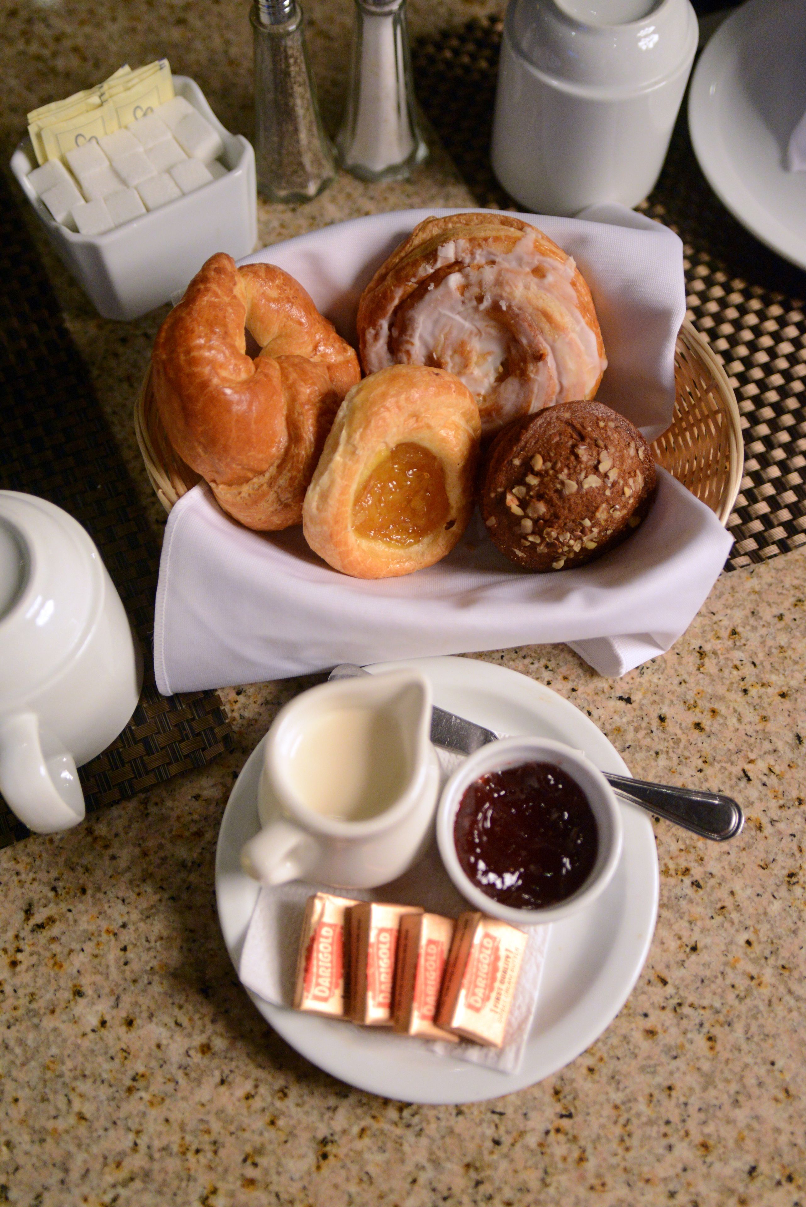 Desayuno con bollos, mantequilla, mermelada y té.