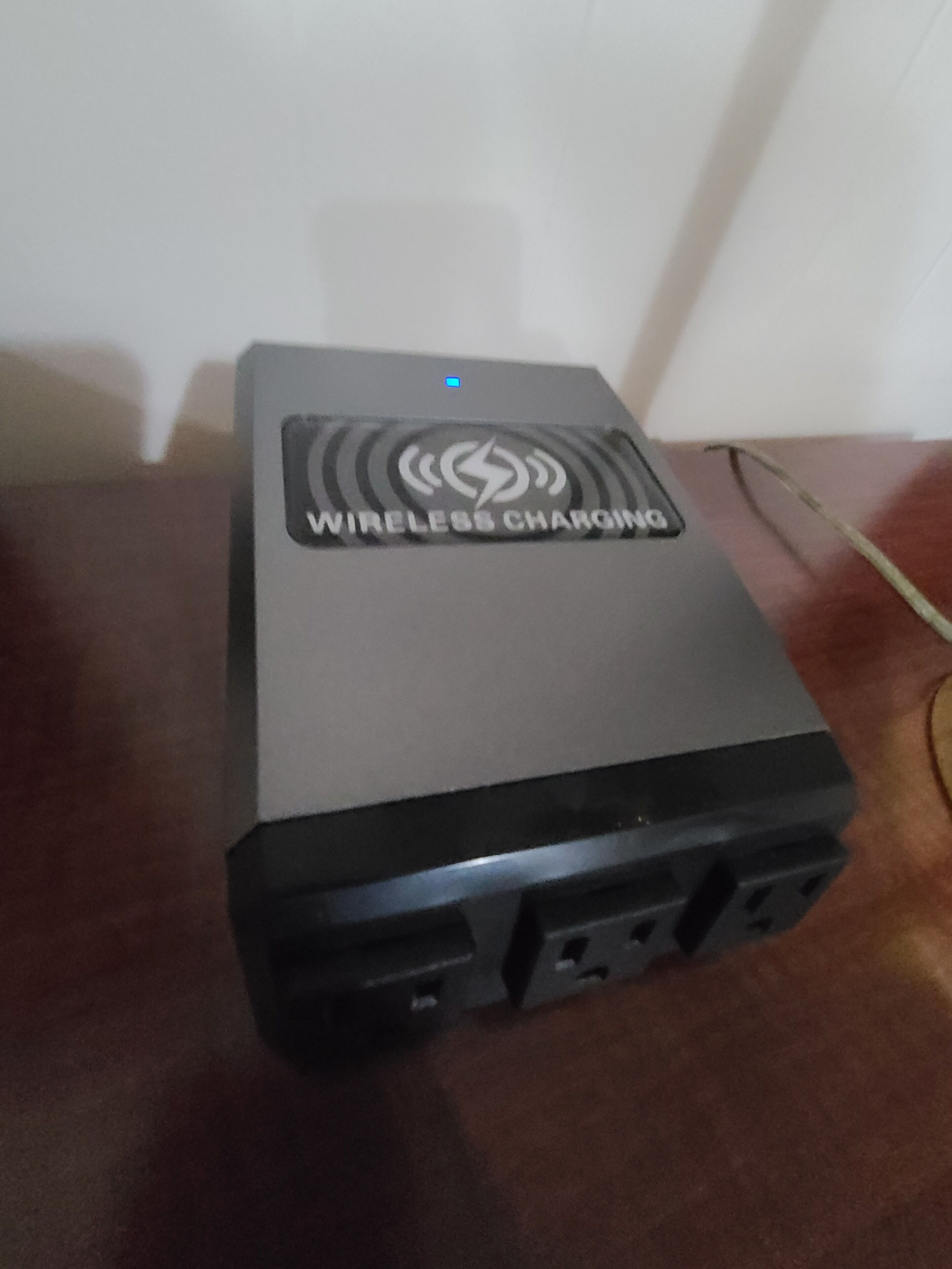 A wireless charging station with a logo and a power outlet.