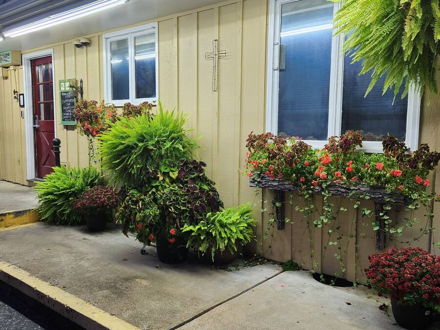 A hotel exterior with a sign listing amenities like laminate floors, family rooms, and an outdoor pool.
