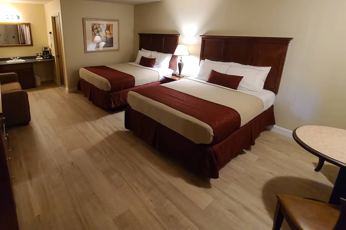 Une chambre d’hôtel avec deux lits, un bureau, une chaise et une petite table.