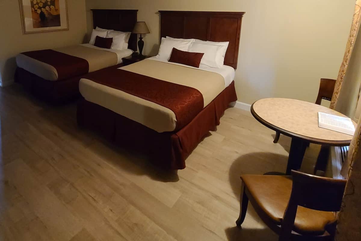 Une chambre d’hôtel avec deux lits, une petite table et une chaise.