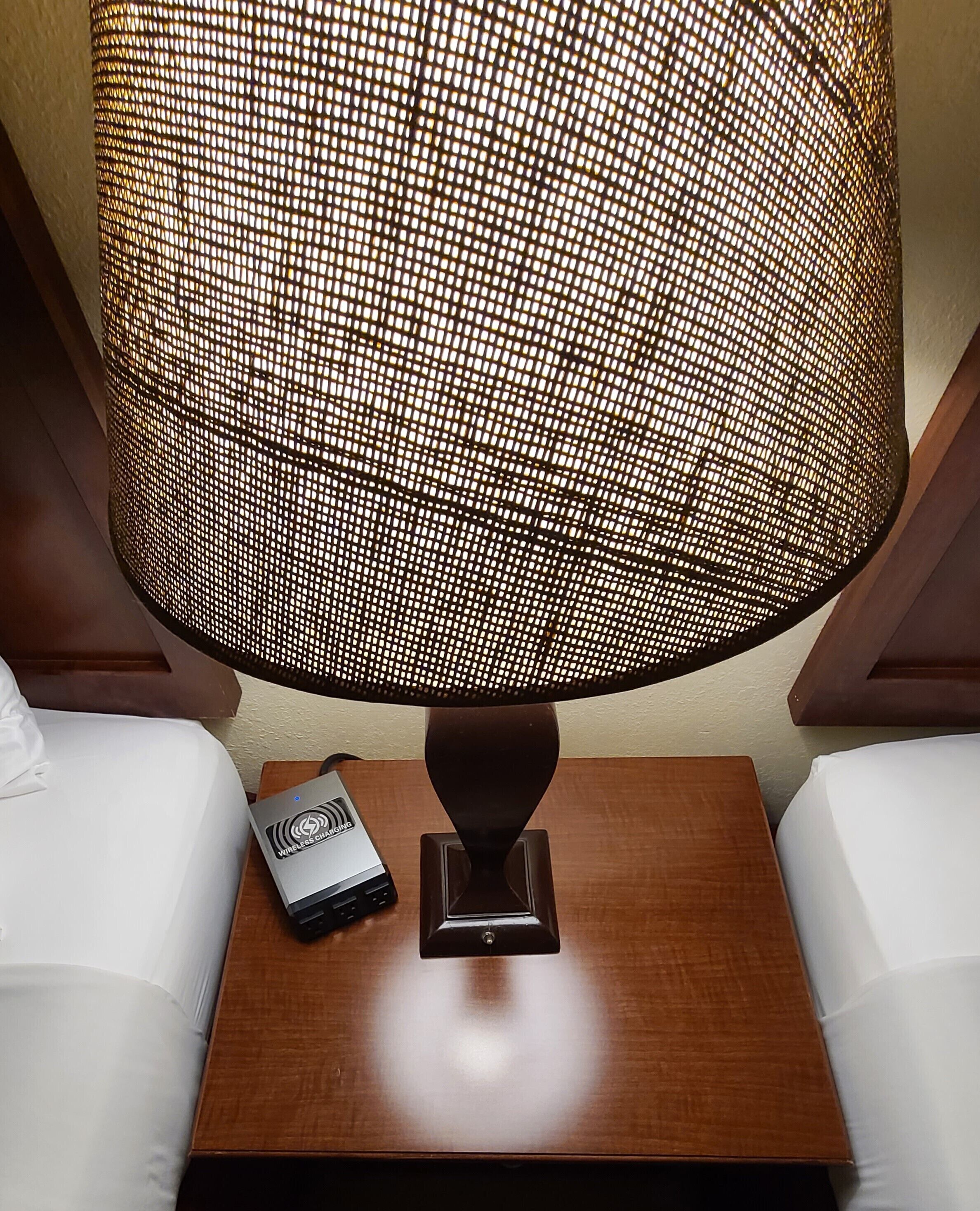Ein Nachttisch mit Lampe, Steckleiste und kabelloser Ladestation.