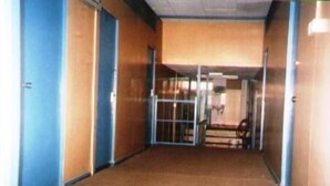 A hallway with a carpeted floor, wooden walls, and a glass door at the end. - ET Budget Guest House (George Town)