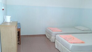A small, simple room with two beds, a wooden desk, and a kettle. - ET Budget Guest House (George Town)