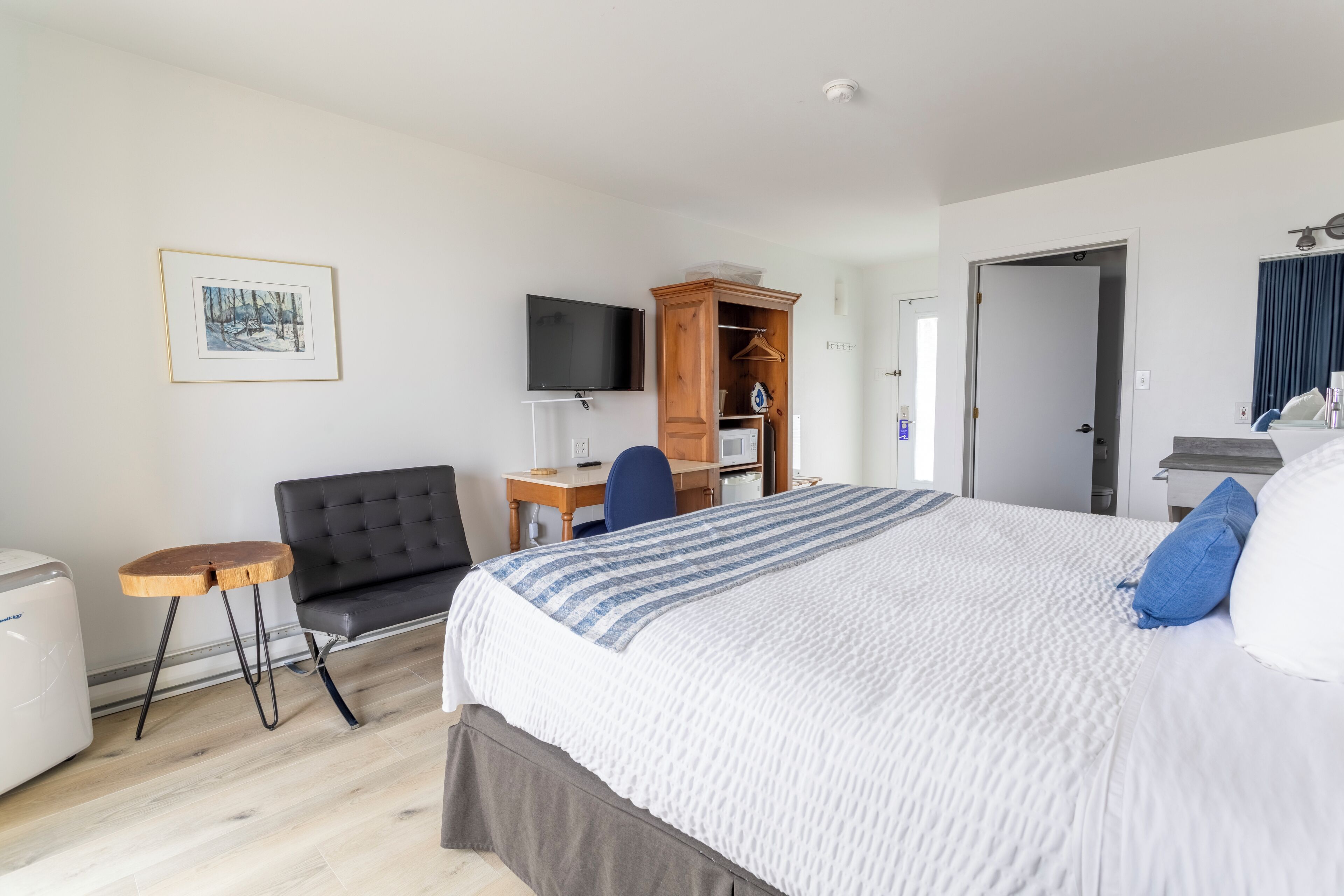 Ein Hotelzimmer mit einem großen Bett, einem Schreibtisch mit Stuhl, einem Fernseher und einem Kleiderschrank.