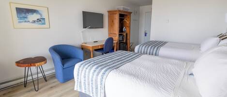 A hotel room with two beds, a desk, a chair, a TV, and a wardrobe.