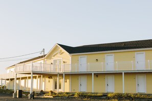 A yellow motel with multiple rooms, a covered porch, and a small balcony.