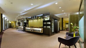 Un hall d’hôtel comprenant un comptoir d’accueil, un espace salon et un aménagement intérieur moderne.