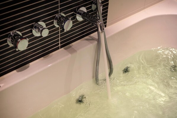 A bathtub with running water and a showerhead. - Van der Valk Hotel Ridderkerk (Ridderkerk)