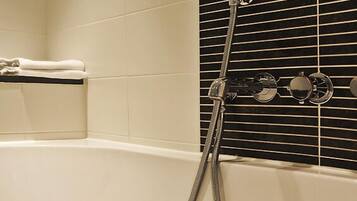 Une baignoire équipée d’un pommeau de douche à main et d’un porte-serviettes.