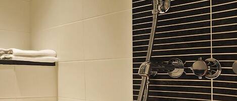A bathtub with a handheld showerhead and a towel rack.