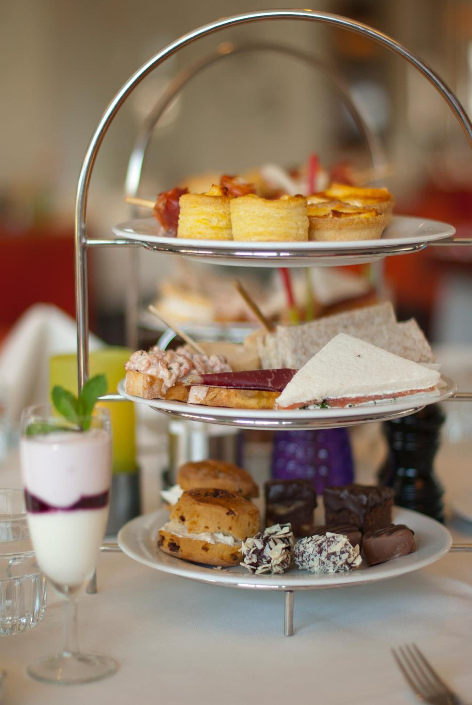 A three-tiered dessert stand with various pastries and sandwiches.