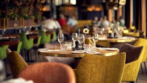 Un restaurant avec des tables rondes disposées pour accueillir les clients, des chaises jaunes et une ambiance chaleureuse.