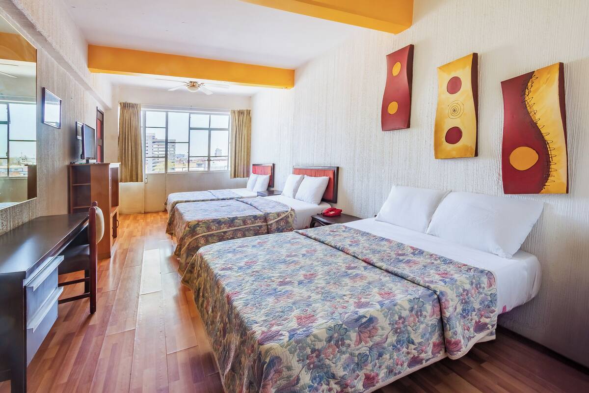 A hotel room with two beds, a desk, and a TV.