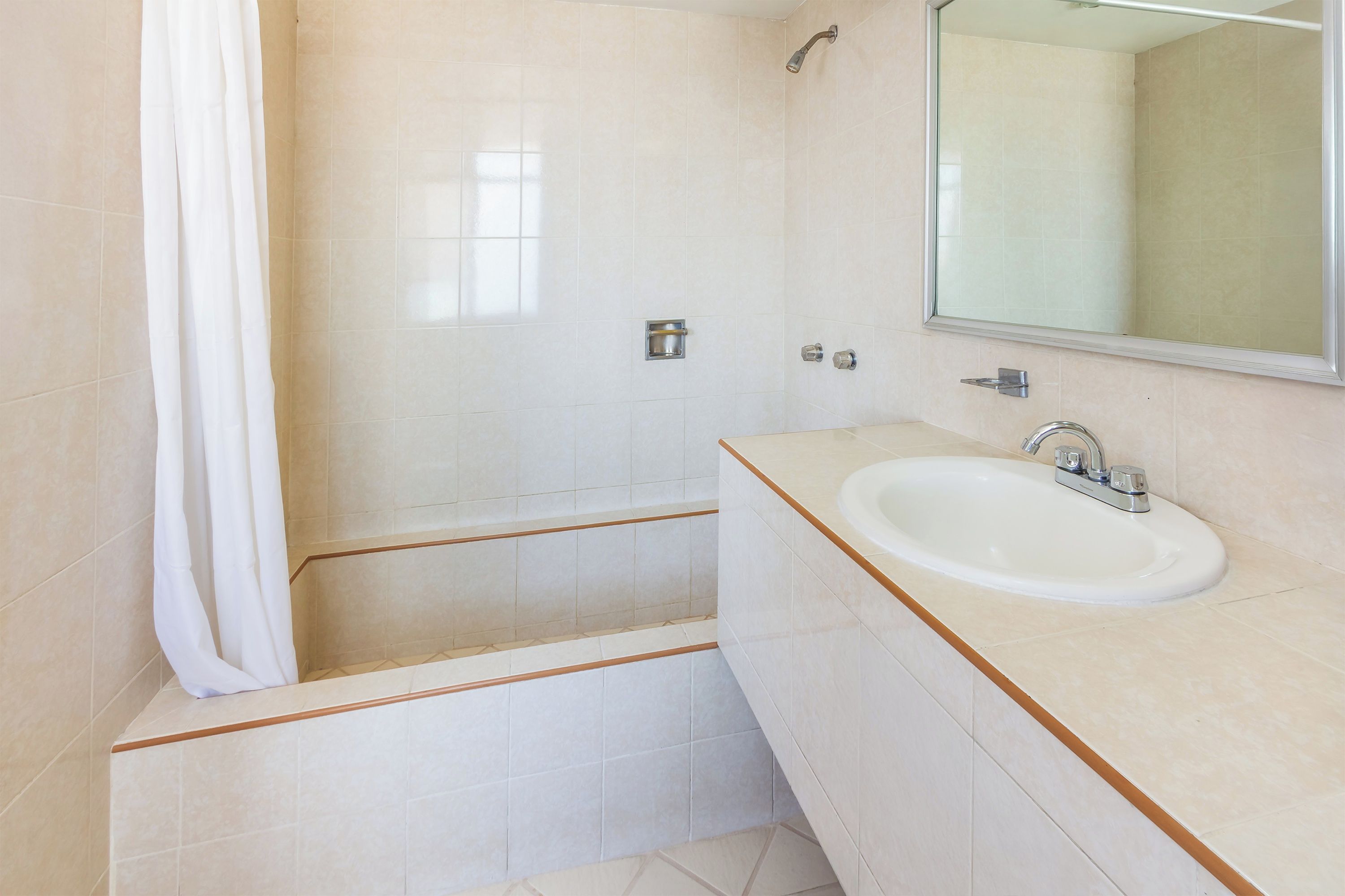 A bathroom with a bathtub, a sink, and a mirror.