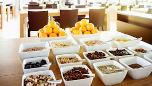 A buffet table with various food items in white bowls, arranged in a cafeteria setting. - Midori The Green Guesthouse (Dossenheim)