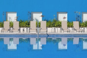 A poolside area with lounge chairs and planters. - One Puerto Vallarta Aeropuerto (Puerto Vallarta)
