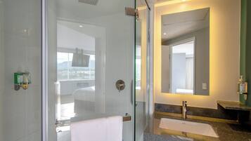 Un baño moderno con cabina de ducha de vidrio, lavabo con tocador y un espejo grande.