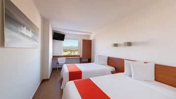 Een hotelkamer met twee bedden, een bureau en een televisie.