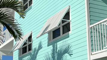 A turquoise multi-story building with balconies and windows.