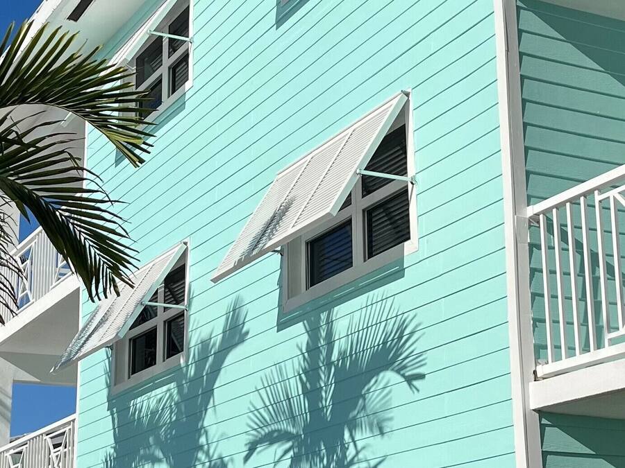 A turquoise multi-story building with balconies and windows.