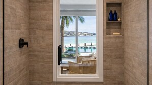 A glass-enclosed shower with a view of a pool and lounge chairs.
