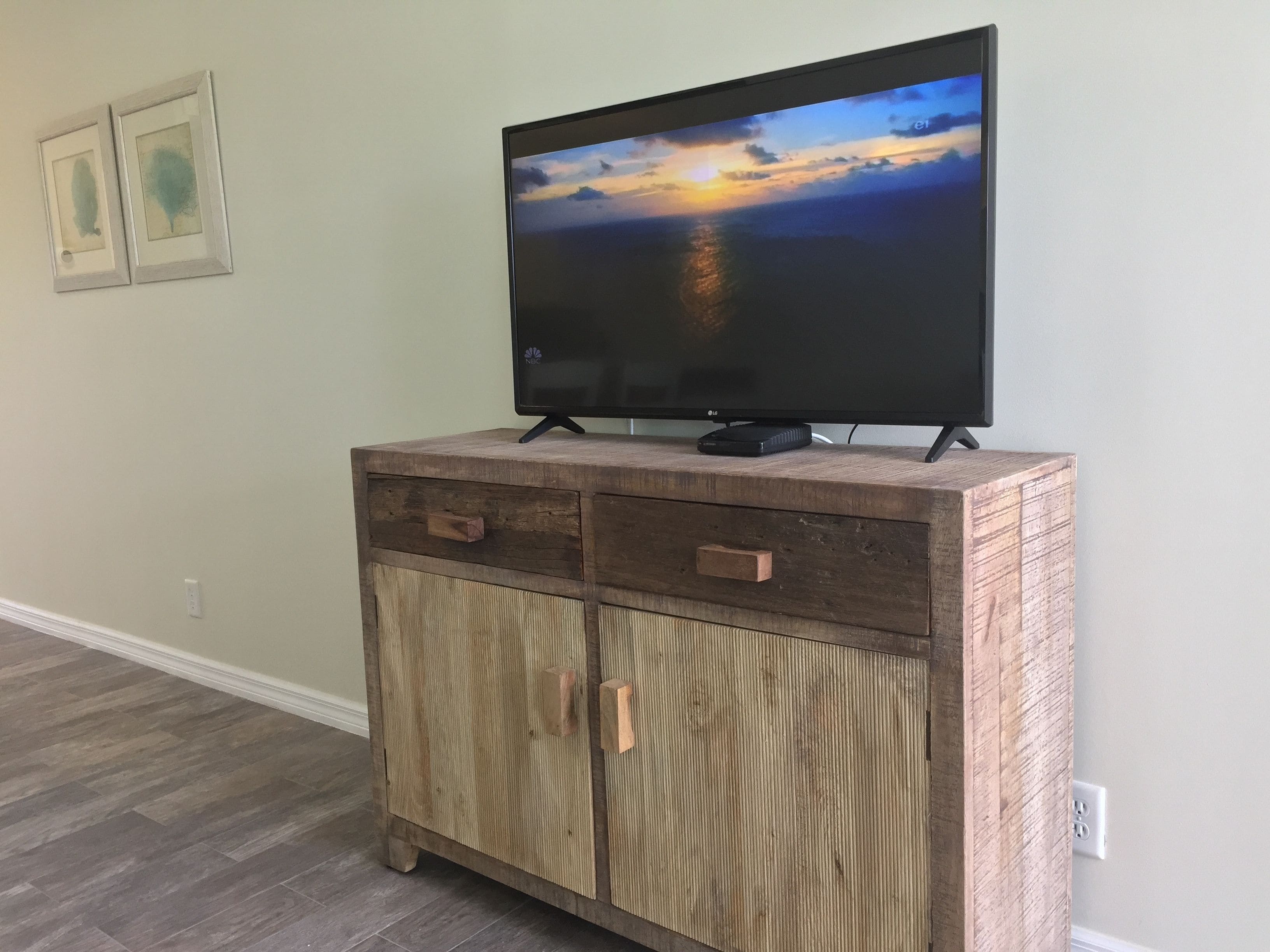 A wooden cabinet with a flat-screen TV on top, drawers, and a cabinet door.