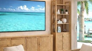 A room with a large ocean view painting, wooden furniture, and a bookshelf.